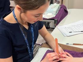 A beauty therapy student conducts a treatment on a client's hands