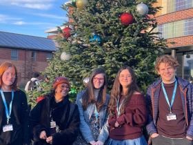Staff and students stand in front of a Christmas tree