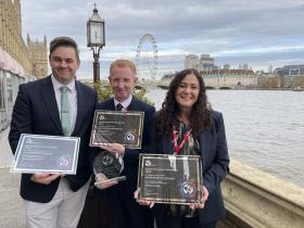 The three nominees stand with their certificates in front of the river Thames.