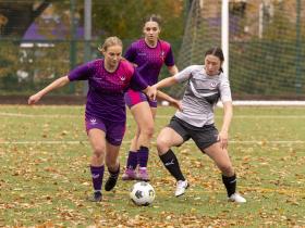 A group of girls playing football on a grass pitch