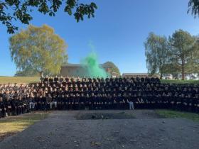 A group photo of the staff, students, and volunteers at the Walesby trip. In the back are trees and a green smoke flare
