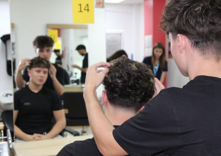 A student and his model look at a haircut in the mirror