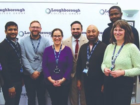 Group of Loughborough College Group Staff standing in a group in front of a College banner