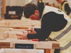 Person wearing high-vis and doing woodwork