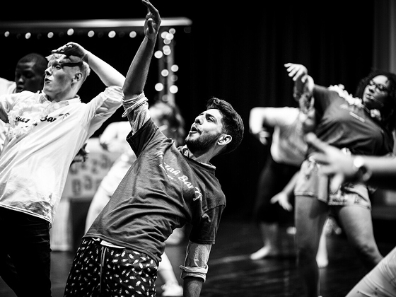 Group of students performing, leaning back and holding their arms up