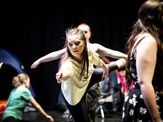 Student holding a dance position, with arms outstretched and one leg raised behind