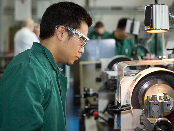 Person wearing safety goggles, working at an industrial machine