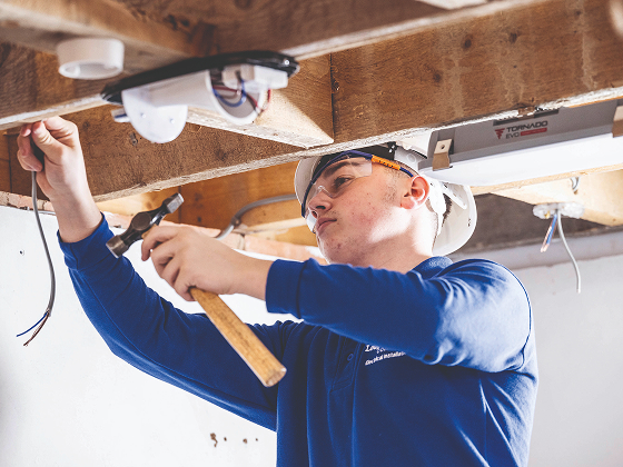Person wearing a helmet and safety goggles, holding a hammer