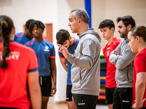 Sport tutor talking to a group of students in a sports hall
