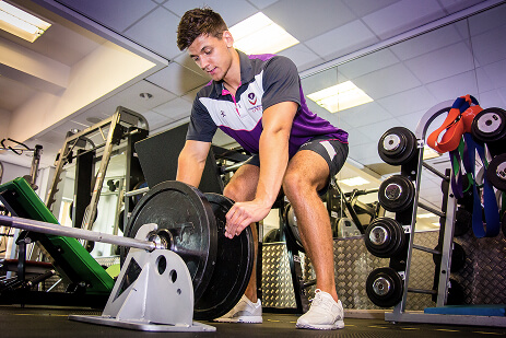 An athlete laying on a therapy table receiving a leg massage