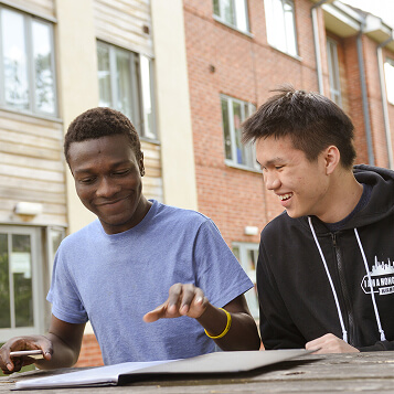 Two international students sitting outside taking to each other