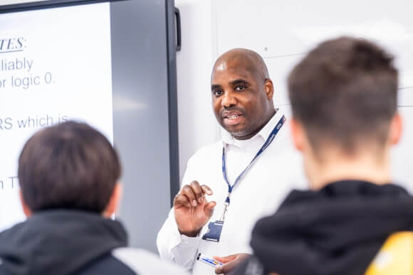 Teacher standing in front of student talking to them