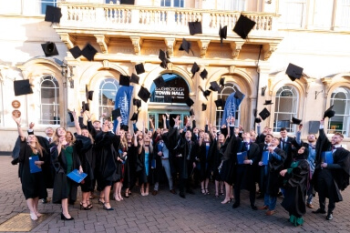 Students dressed in graduation gowns celebrating graduating
