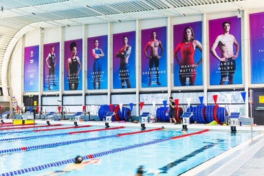 Interior photo of the Loughborough University swimming pool showing banners on the wall of successful former students