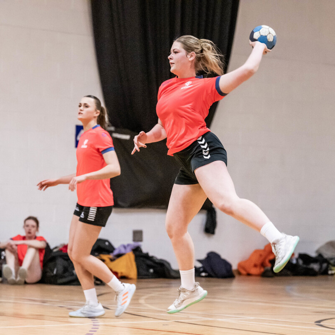 Student jumping while holding a ball