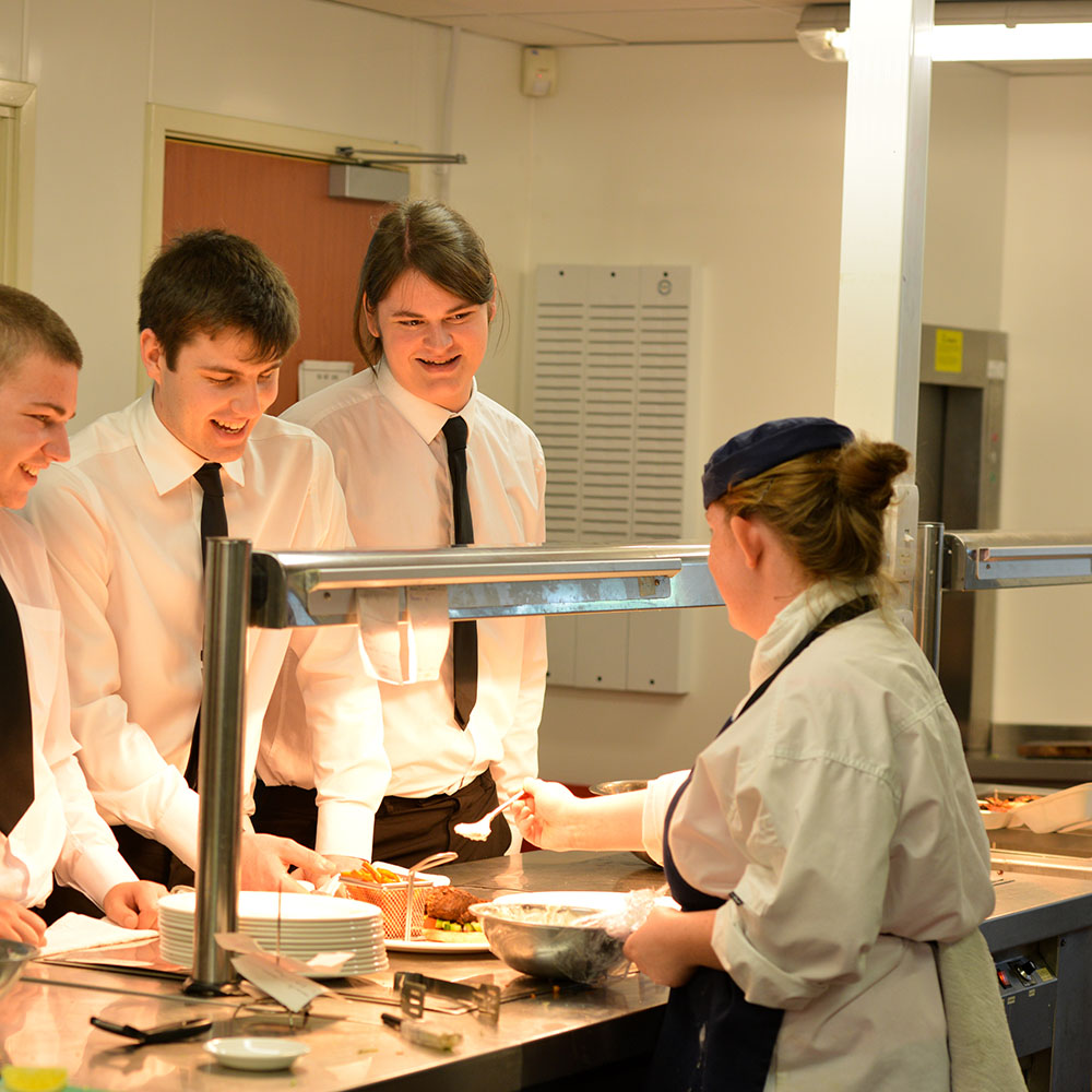 A group of students being instructed by a chef