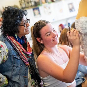 An art teacher offering advice to a student while they're working on project work