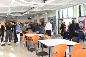 A room filled with children and their parents visiting an Open Day and taking to Loughborough College Group staff