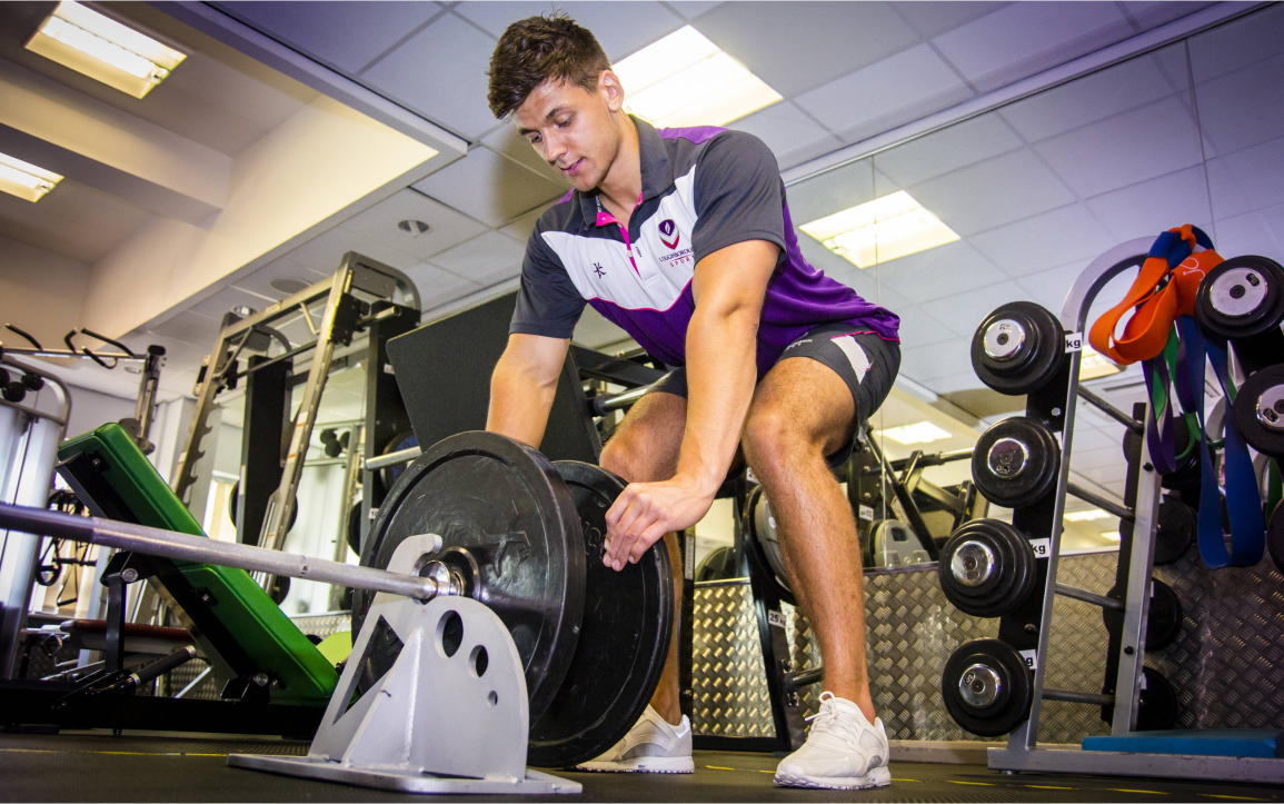 A man placing a weight plate on a barbell