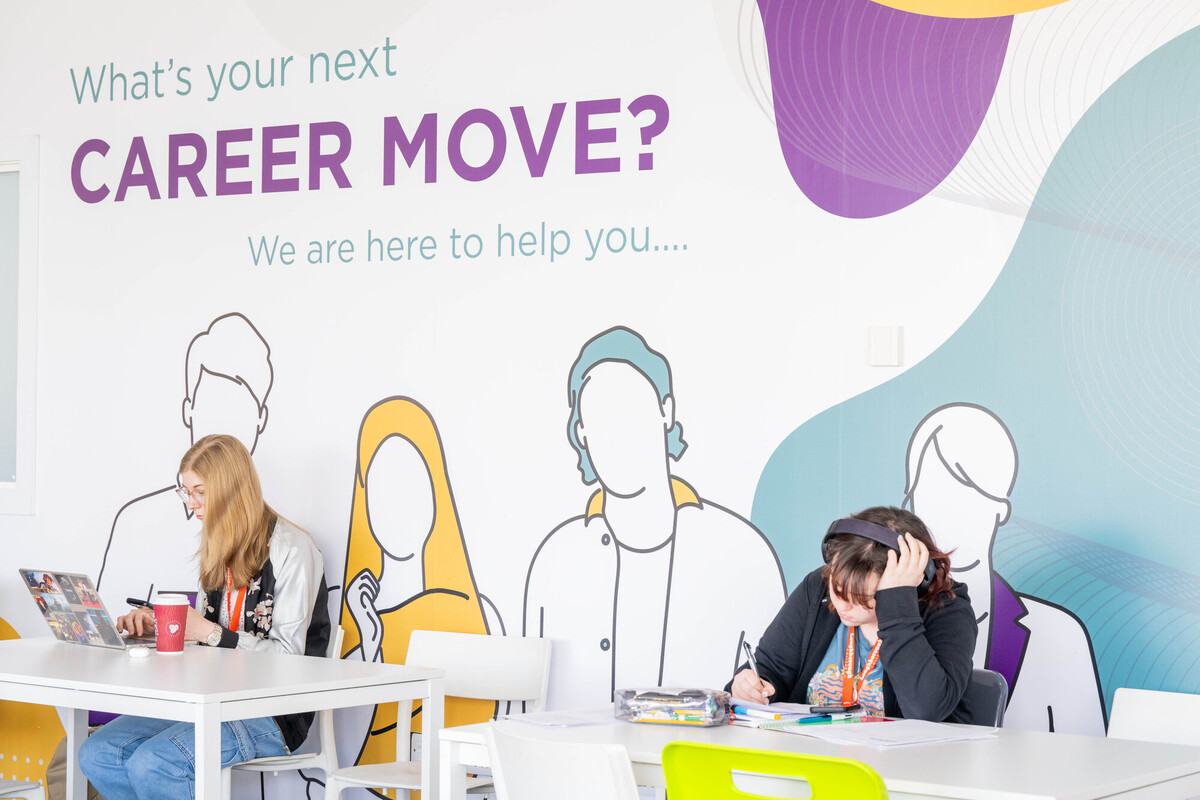 People working at desks under a wall mural reading 'What's your next career move? We are here to help you'